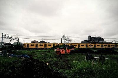 Houses on field against cloudy sky