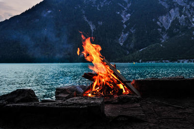 Bonfire against lake and mountain