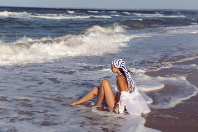 Woman in a white bathing suit and hat sunglasses on an empty sandy beach