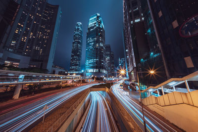 Light trails on road amidst buildings in city at night