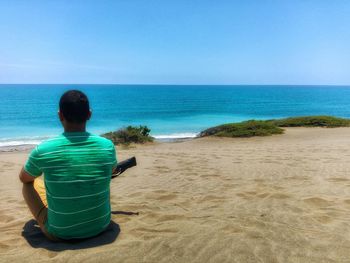 Rear view of man sitting on beach