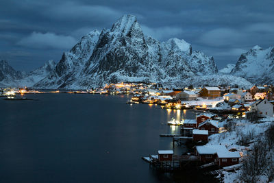 Scenic view of lake by snowcapped mountains at dusk