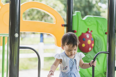 A pretty smiling girl is happily climbing in the playground at adventure park.