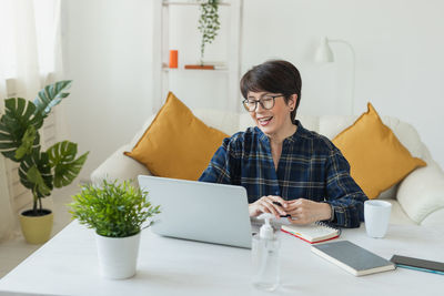 Portrait of young woman using digital tablet while sitting on bed at home