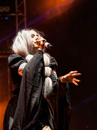 Woman with arms raised standing on stage