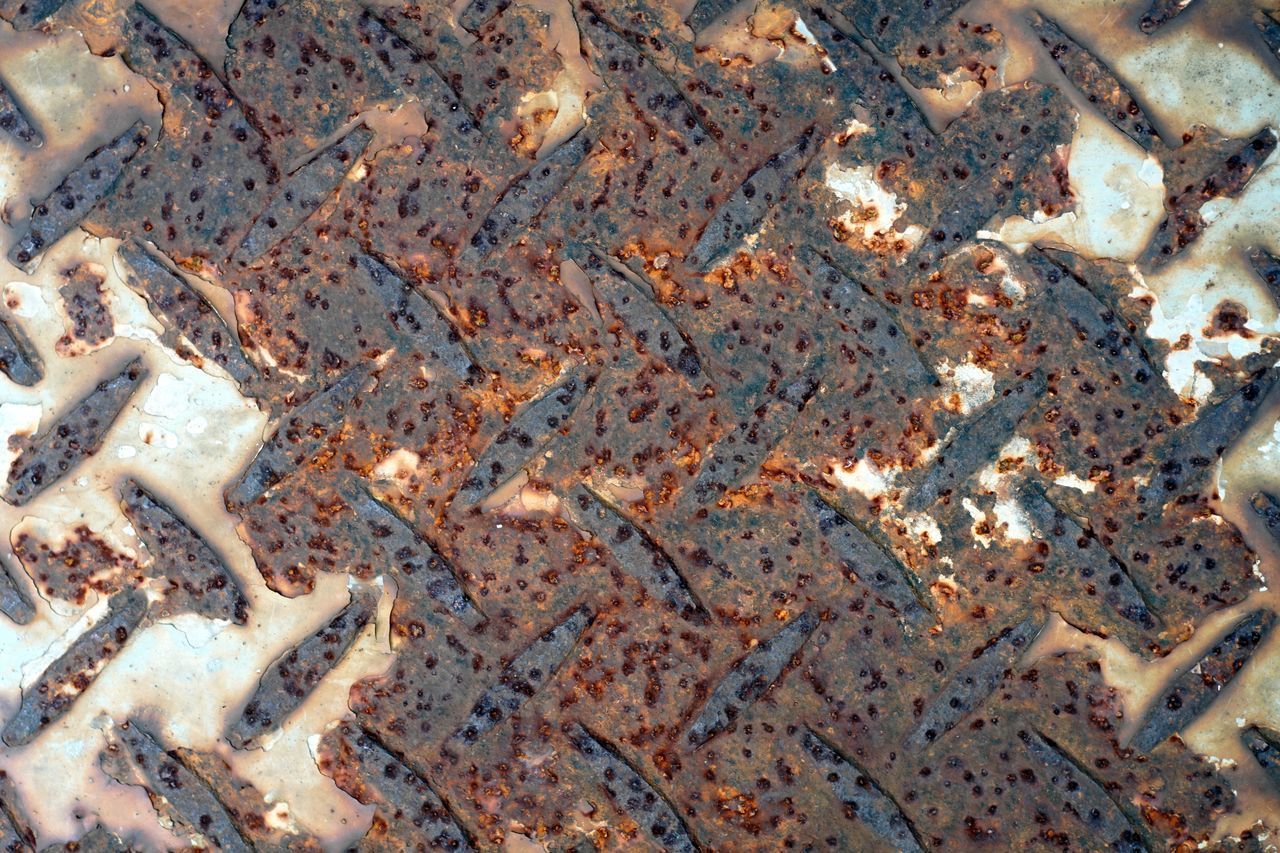 HIGH ANGLE VIEW OF RUSTY METAL ON TEXTURED SURFACE