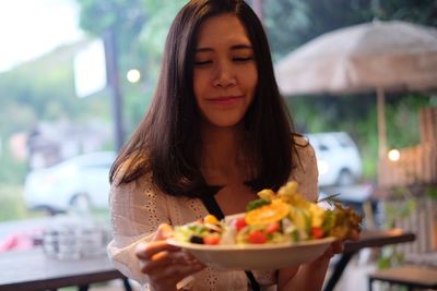 Young woman holding ice cream on table in restaurant