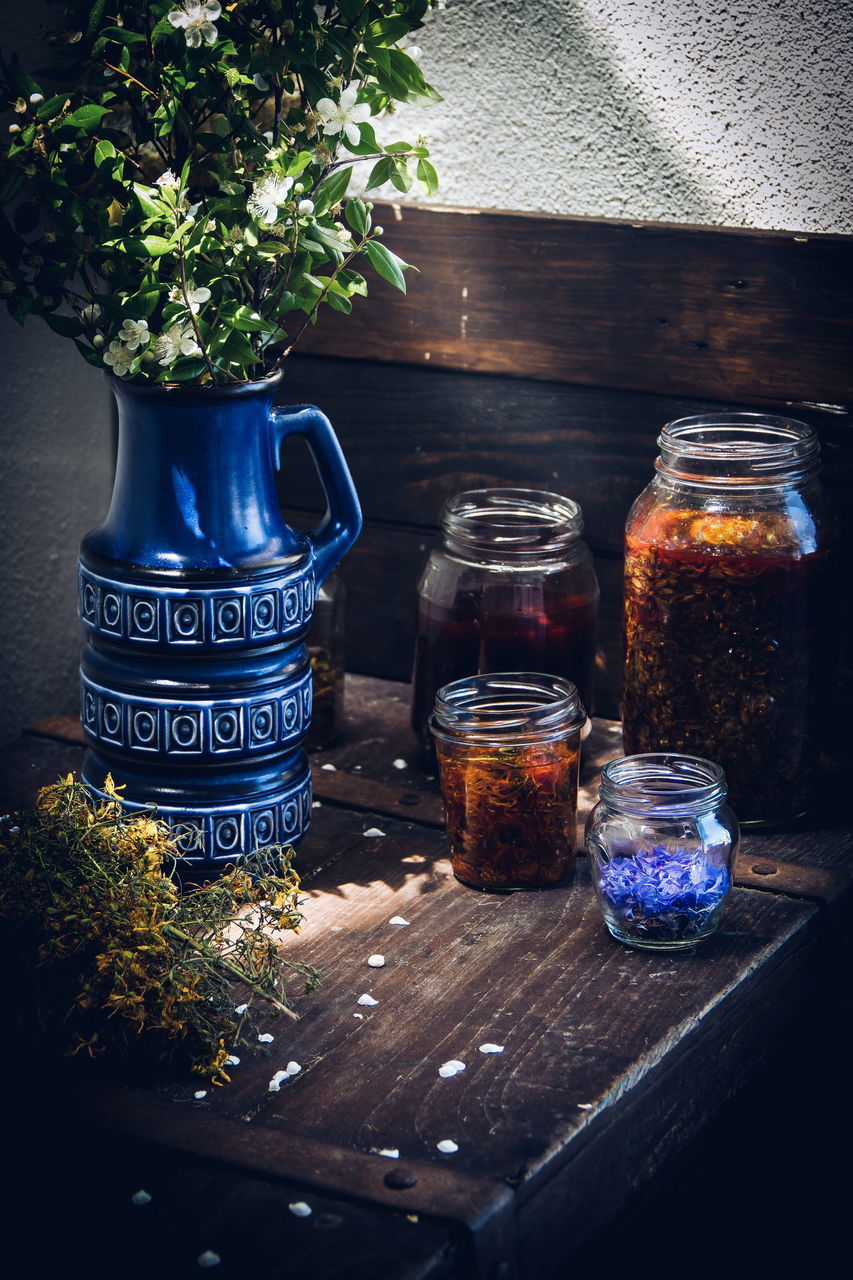 CLOSE-UP OF GLASS JAR ON TABLE BY PLANTS