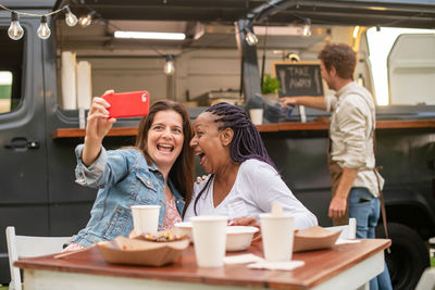 Happy diverse women taking selfie against foot truck