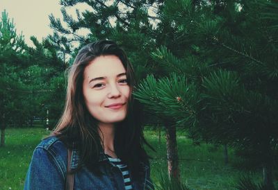 Portrait of smiling young woman against trees
