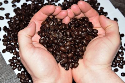 Cropped hands of man holding roasted coffee beans in heart shape