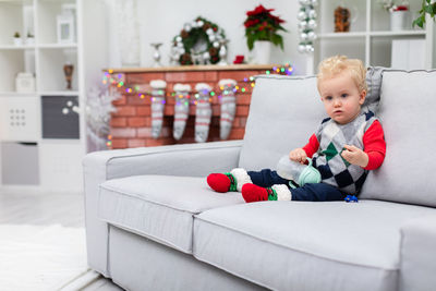 Portrait of smiling boy sitting on sofa at home