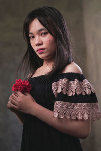 Beautiful young woman standing against red rose