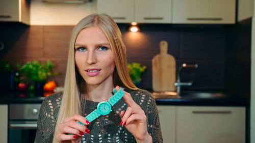 Portrait of woman holding wristwatch at home