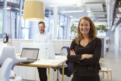 Portrait of confident businesswoman standing with arms crossed at office
