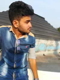 Thoughtful young man looking away while sitting outdoors