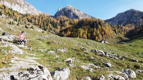 Rear view of person by rocks against mountains