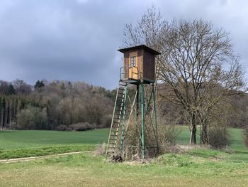 Hunters perch on field against sky