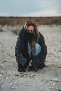 Portrait of young woman sitting on land