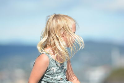 Girl with blond hair against sky