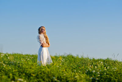 Woman standing on field against clear sky