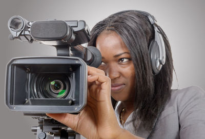 Woman photographing against gray background