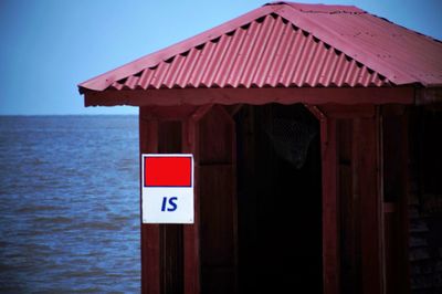 Information sign on building by sea against sky