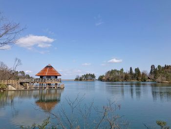 Houses by lake and trees against sky