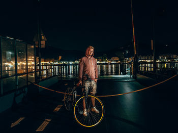 Portrait of smiling standing against illuminated building at night