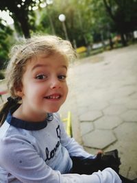 Portrait of cute smiling girl sitting at playground