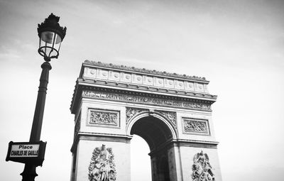 Low angle view of gas light and arc de triomphe against sky