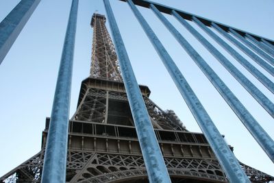 Low angle view of eiffel tower seen through railing against sky