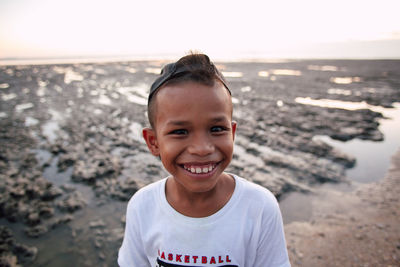 Portrait of smiling boy on beach against sky