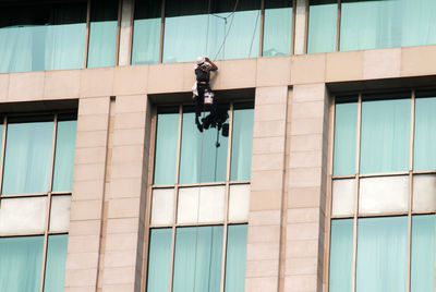 A worker cleaning window glass of a high rise building corporate office