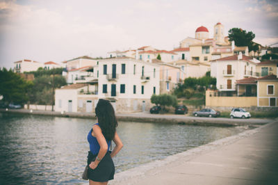 Rear view of woman looking at building while standing by lake