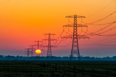 Electricity pylon on field against sky during sunset