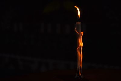 Close-up of burning candle at night