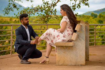 Full length of couple sitting outdoors