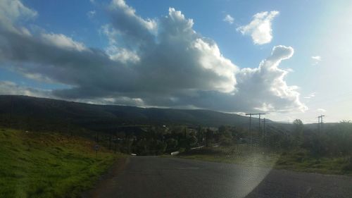 Road passing through landscape against cloudy sky