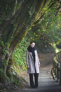 Full length of young woman standing in forest