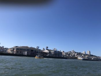 Sea by buildings against clear blue sky