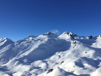 Scenic view of snowcapped mountains against clear blue sky