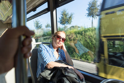 Mid adult woman wearing sunglasses sleeping at bus