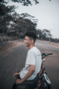 Side view of young man sitting on road