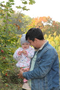 Rear view of friends standing against plants
