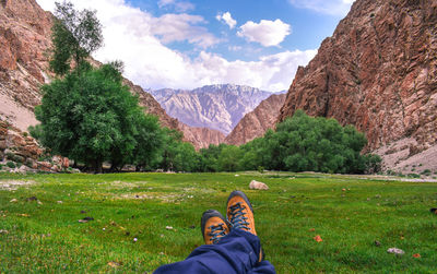Low section of man on mountain against sky