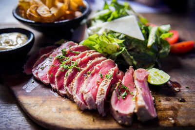 Close-up of chopped vegetables and tuna steak on cutting board