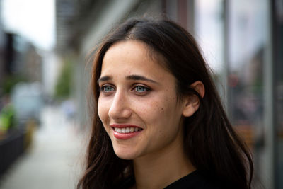 Smiling young woman looking away while standing on footpath