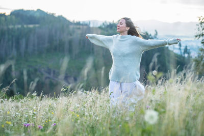 Side view of woman with arms outstretched on field