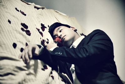 High angle view of young man holding flower while lying on bed at home